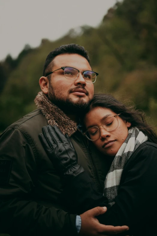 a man and a woman standing next to each other, a picture, pexels, wavy long black hair and glasses, comforting, an olive skinned, embracing