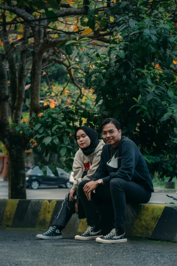 a man and a woman sitting on a bench, by Basuki Abdullah, unsplash, realism, against the backdrop of trees, casual pose, smirking, concert