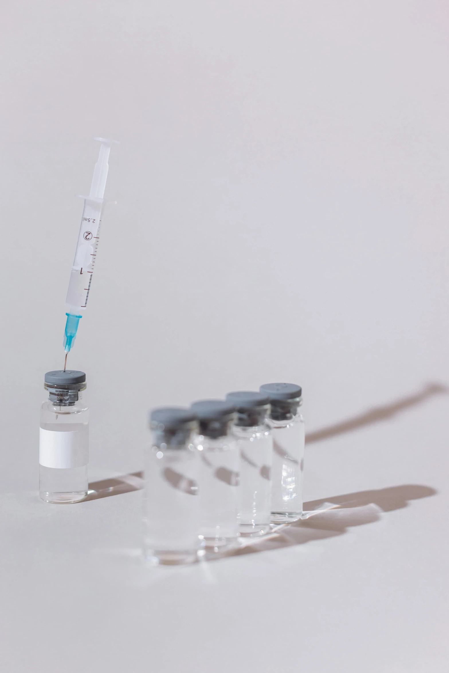 a syll sitting on top of a table next to a bottle, pexels, syringe, on a gray background, clones, detailed acrylic