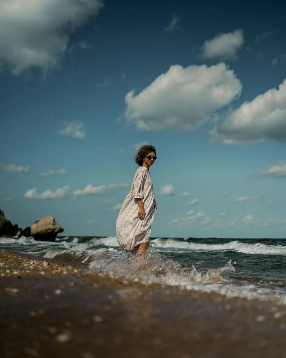 a woman standing on top of a beach next to the ocean, in the water