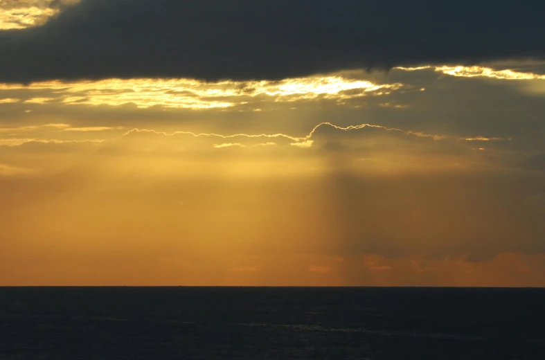 the sun is shining through the clouds over the ocean, a picture, pexels contest winner, romanticism, god light shafts, patches of yellow sky, shot from a distance, taken in the late 2010s