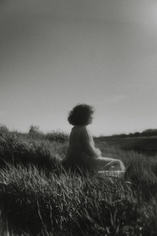 a black and white photo of a woman sitting in a field, unsplash, conceptual art, grainy movie still, alternate album cover, sittin, sun puddle