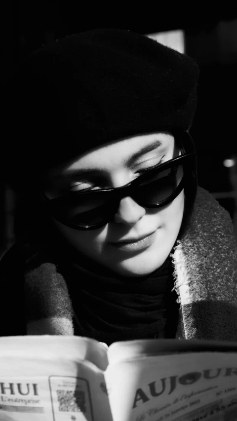 a black and white photo of a woman reading a book, inspired by Lillian Bassman, purism, wearing sunglasses and a cap, maisie williams, wrapped in a black scarf, avatar image