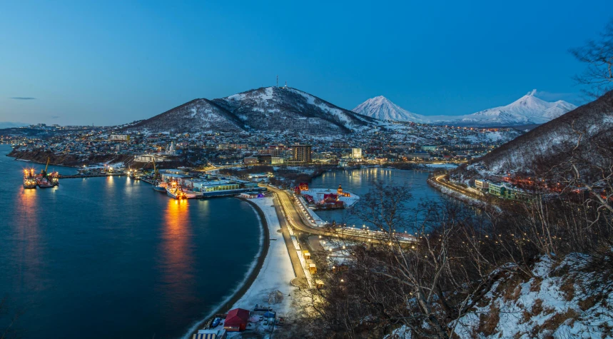 a large body of water surrounded by snow covered mountains, beautifully lit buildings, cheburashka, port city, thumbnail