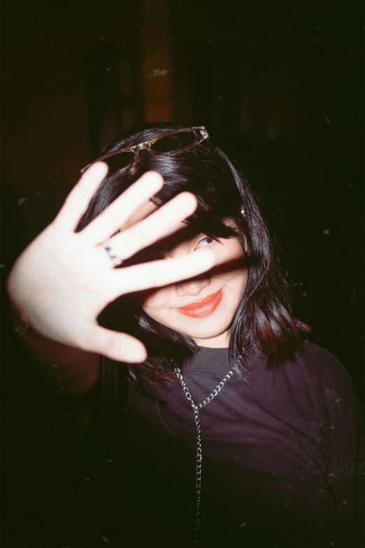 a woman holding her hands up in front of her face, an album cover, unsplash, sarah andersen, taken with a disposable camera, with black eyes, ulzzang