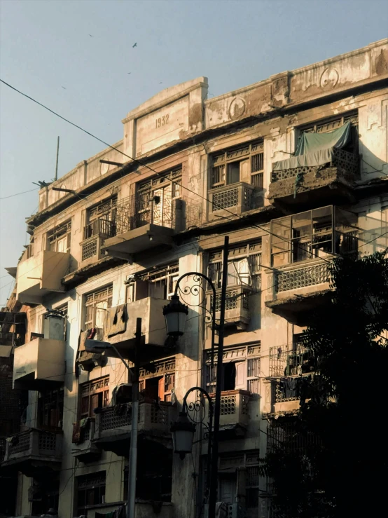 a tall building with lots of windows and balconies, a photo, bengal school of art, 1990s photograph, “derelict architecture buildings, art deco era), in the evening