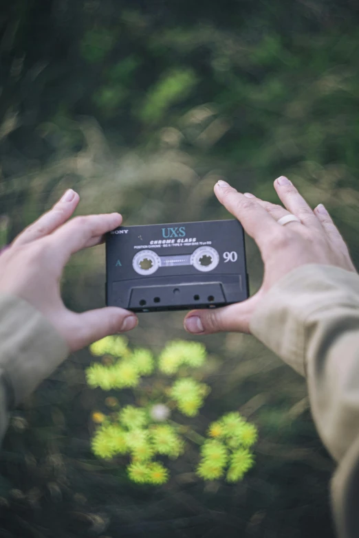 a person taking a picture of a cassette player, an album cover, by Sebastian Vrancx, unsplash, photograph captured in the woods, historical footage, videotape still from 1985, 268435456k film