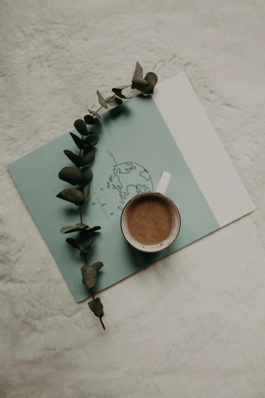 a cup of coffee sitting on top of a piece of paper, a drawing, by Alice Rahon, pexels contest winner, postminimalism, made of leaves, milk and mocha style, teal aesthetic, bed of flowers on floor