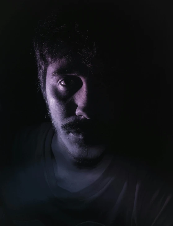 a man sitting in front of a laptop computer, a character portrait, by Adam Rex, pexels contest winner, spooky lighting, discord profile picture, with haunted eyes and curly hair, shadow of beard