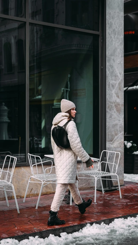 a person walking down a sidewalk in the snow, standing in a restaurant, with a backpack, milk and mocha style, model wears a puffer jacket