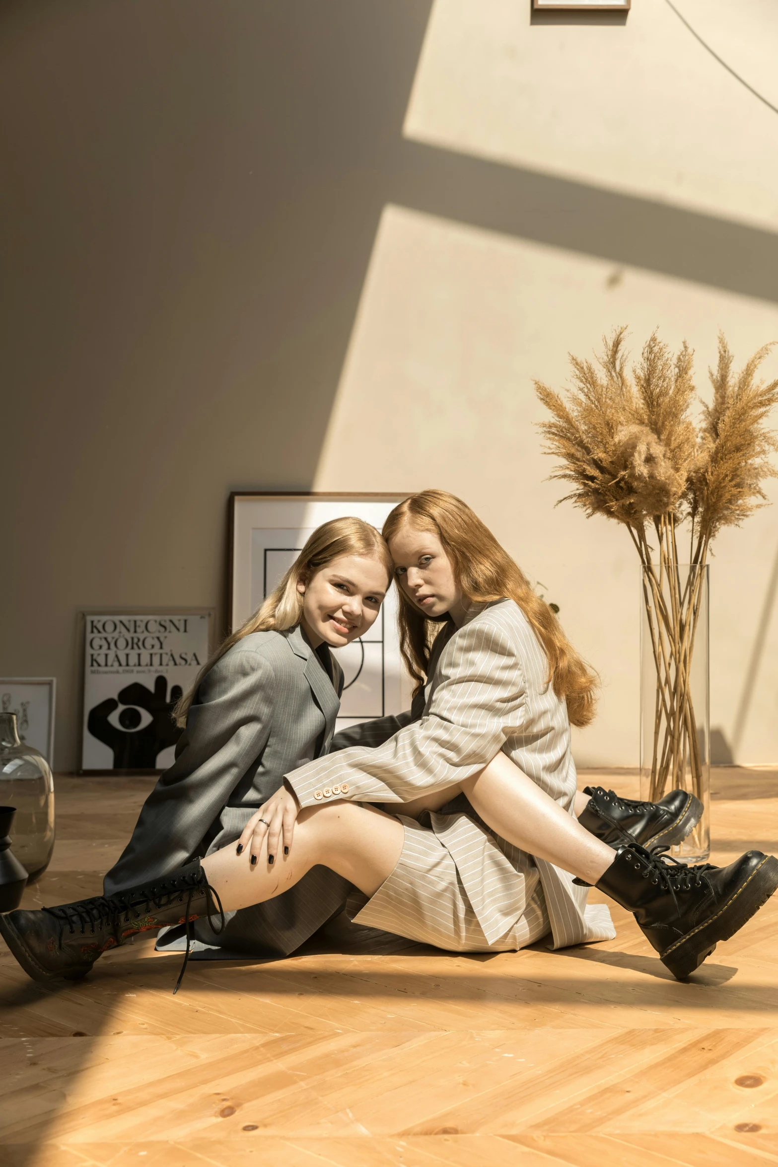 a couple of women sitting on top of a wooden floor, trending on pexels, realism, wearing black boots, 🌺 cgsociety, bright daylight indoor photo, sakimichan