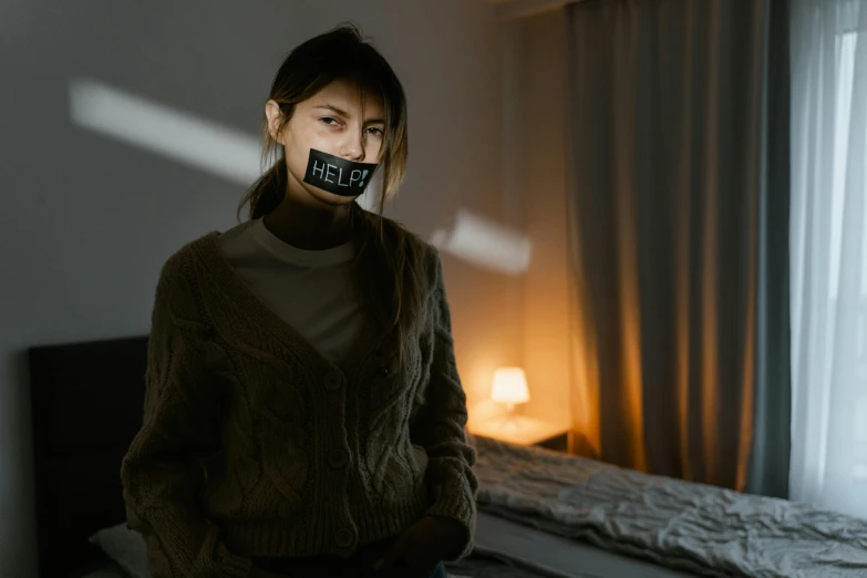 a woman sitting on a bed with a tape over her mouth, a hologram, inspired by Elsa Bleda, trending on pexels, woman holding sign, hello darkness my old friend, no lights in bedroom, hell with people suffering