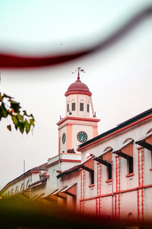 a red and white building with a clock tower, trending on pexels, quito school, kalighat, cinematic still, square, south jakarta