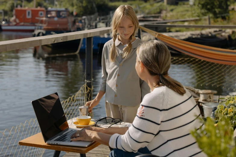 a couple of women sitting at a table with a laptop, by Jørgen Roed, pexels contest winner, plein air, small dock, still from a live action movie, family photo, programming