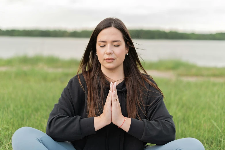 a woman sitting in the grass with her eyes closed, a portrait, unsplash, hurufiyya, meditating in lotus position, profile image, portrait image, lakeside