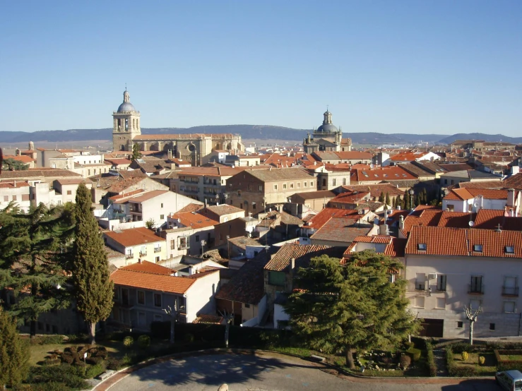 a view of a town from the top of a hill, a photo, by Juan Giménez, baroque, square, white, sunny day time, black