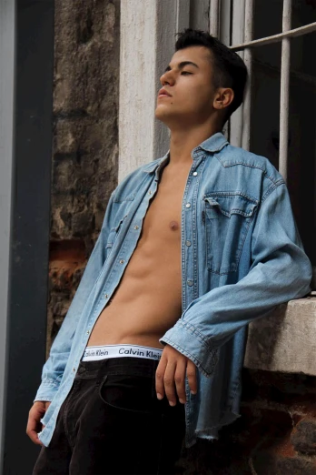 a shirtless man leaning against a window, an album cover, inspired by Carlos Berlanga, trending on unsplash, wearing double denim, non binary model, korean muscle boy 2 1 years old, asian man