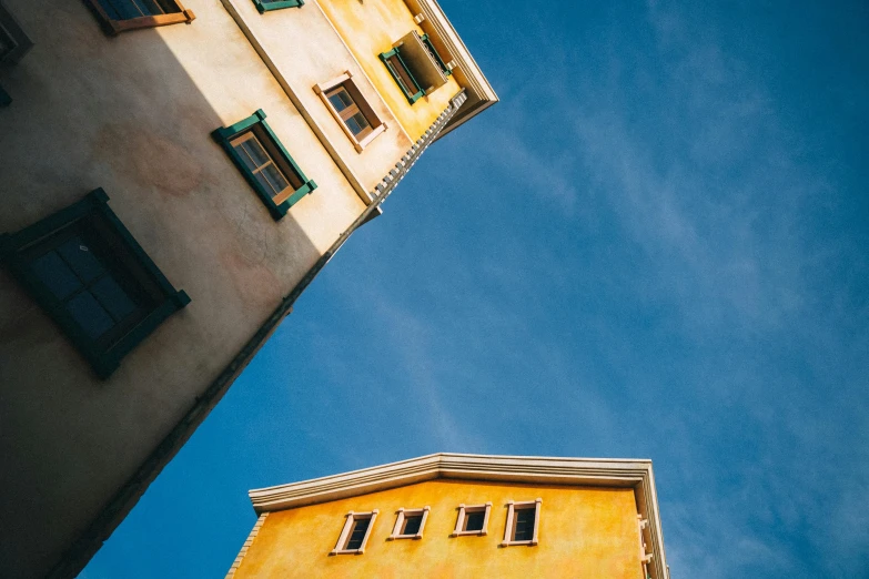 a couple of buildings that are next to each other, a picture, unsplash contest winner, pale yellow walls, dynamic low angle shot, colorful photo, ocher