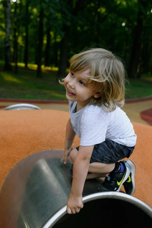 a little boy sitting on top of a metal slide, unsplash, spherical, walking at the park, a blond, square