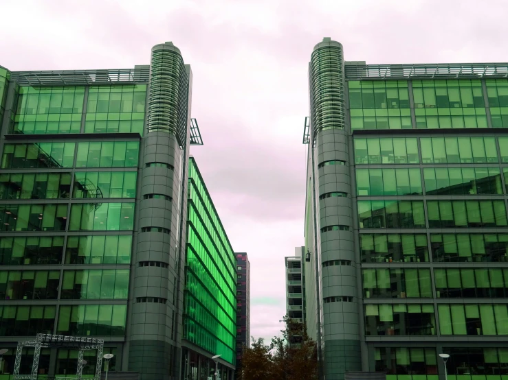 a couple of tall buildings sitting next to each other, inspired by Luigi Kasimir, unsplash, modernism, large green glass windows, glasgow, low quality photo, taken in the 2000s