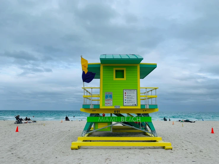 a lifeguard tower sitting on top of a sandy beach, by Carey Morris, unsplash contest winner, hyperrealism, green and yellow, miami, square, green flags