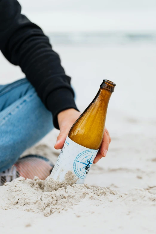 a person sitting in the sand with a bottle of beer, stone ocean, white wine bottle, blue print, uncrop