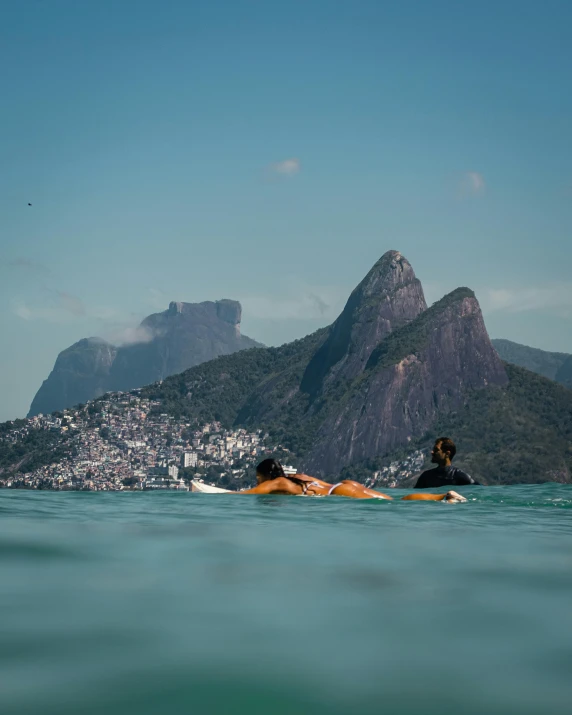 a couple of people riding surfboards on top of a body of water, rio de janeiro, profile image