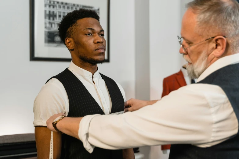 a man putting a tie on another man's neck, pexels contest winner, renaissance, technical suit, man is with black skin, wearing a vest top, academic clothing