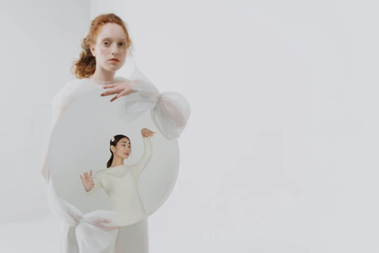 a woman in a white dress holding a mirror, an album cover, inspired by Anna Füssli, issey miyake, eleanor tomlinson, two women, round-cropped