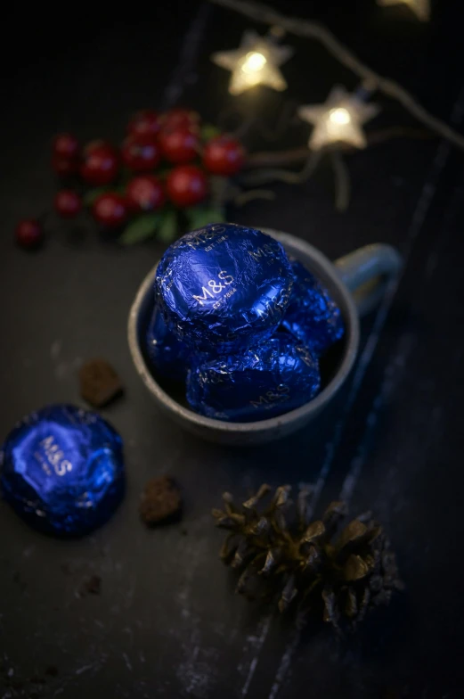 a cup filled with blue chocolate sitting on top of a table, metallic asteroid, christmas, full product shot, rich deep colours