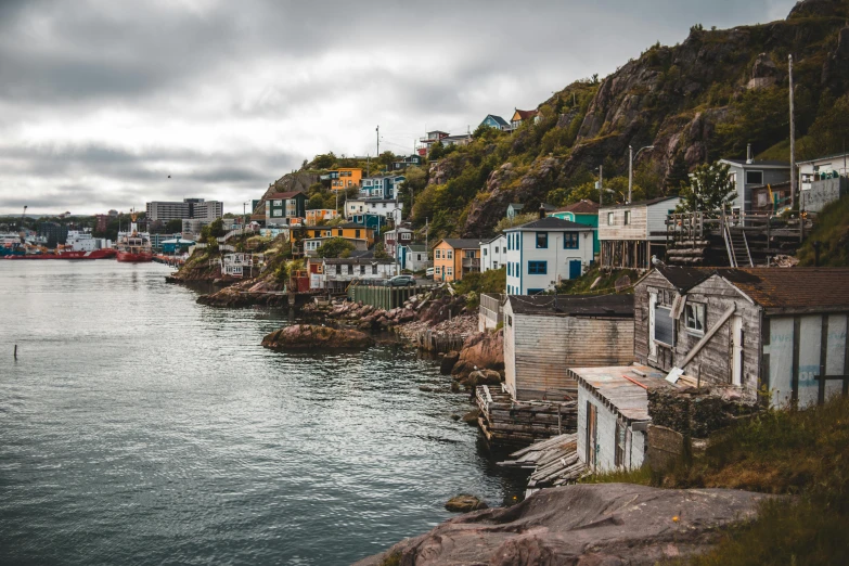 a number of houses near a body of water, a colorized photo, pexels contest winner, inuit heritage, coastal cliffs, maple syrup sea, vibrant but dreary
