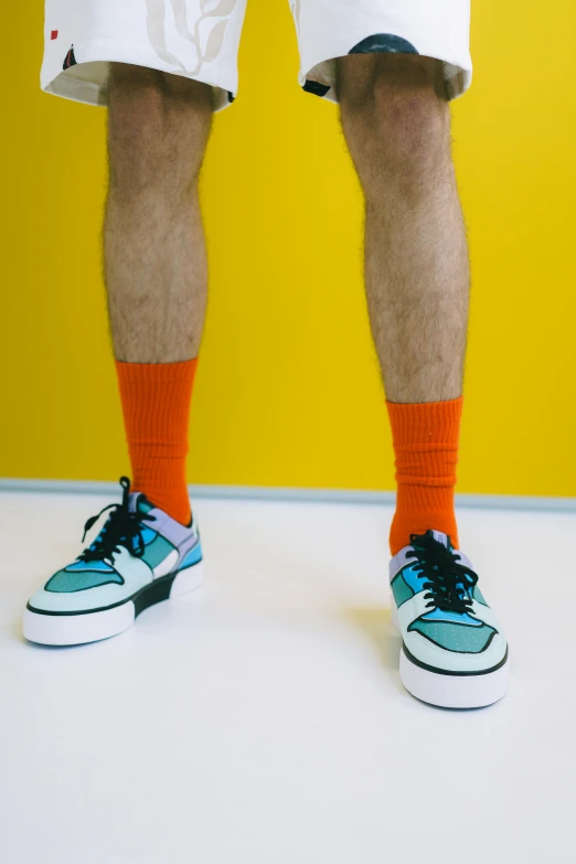 a man standing in front of a yellow wall, unsplash, maximalism, wearing kneesocks, coloured in teal and orange, wearing white sneakers, plain background