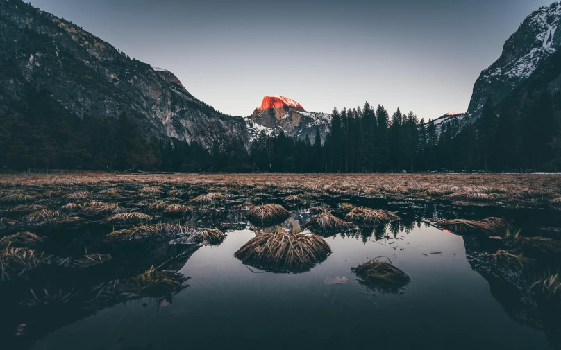 a mountain is reflected in a puddle of water, unsplash contest winner, yosemite, red peaks in the background, filtered evening light, minimal background