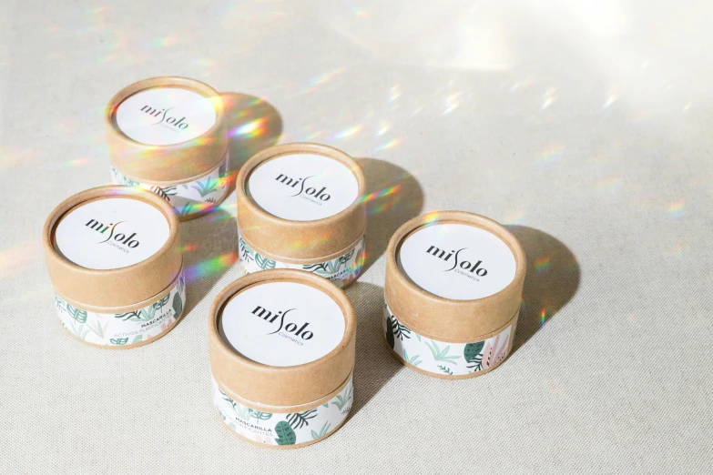 a group of four cups sitting on top of a table, inspired by Eden Box, holography, natural make-up, hayao, sun dappled, labels