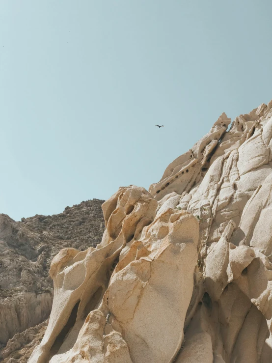 a bird that is flying over some rocks, in the desert, rock climbing, unsplash 4k, multiple stories