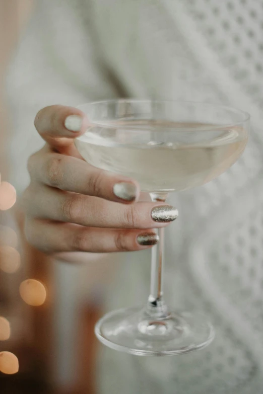 a close up of a person holding a wine glass, inspired by Ndoc Martini, gleaming silver, unclipped fingernails, holiday, champagne