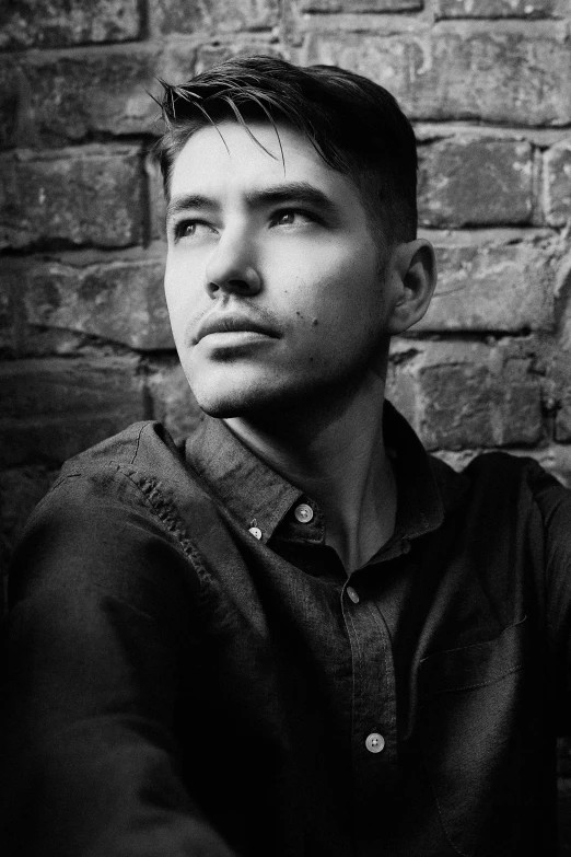 a man sitting in front of a brick wall, a black and white photo, pexels contest winner, art nouveau, portrait of a rugged young man, mark edward fischbach, liam brazier and nielly, headshot profile picture