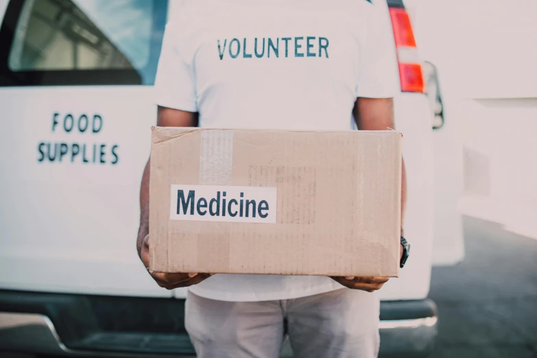 a man holding a box in front of a van, by Meredith Dillman, pexels contest winner, renaissance, medical labels, medic, sydney, ::