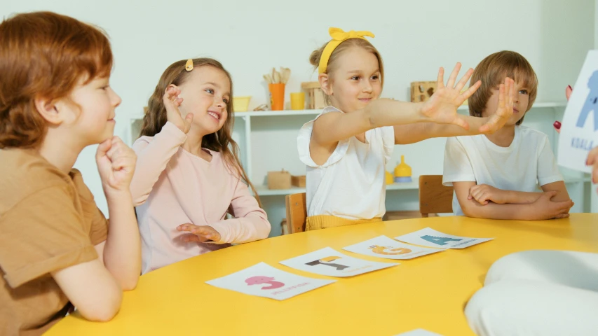 a group of children sitting around a yellow table