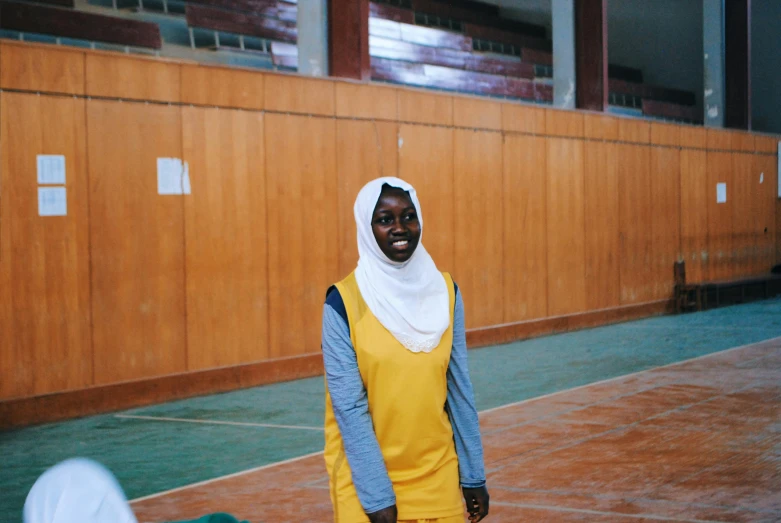 a woman standing on top of a tennis court holding a racquet, an album cover, hurufiyya, in a classroom, wearing basketball jersey, hijab, documentary photo