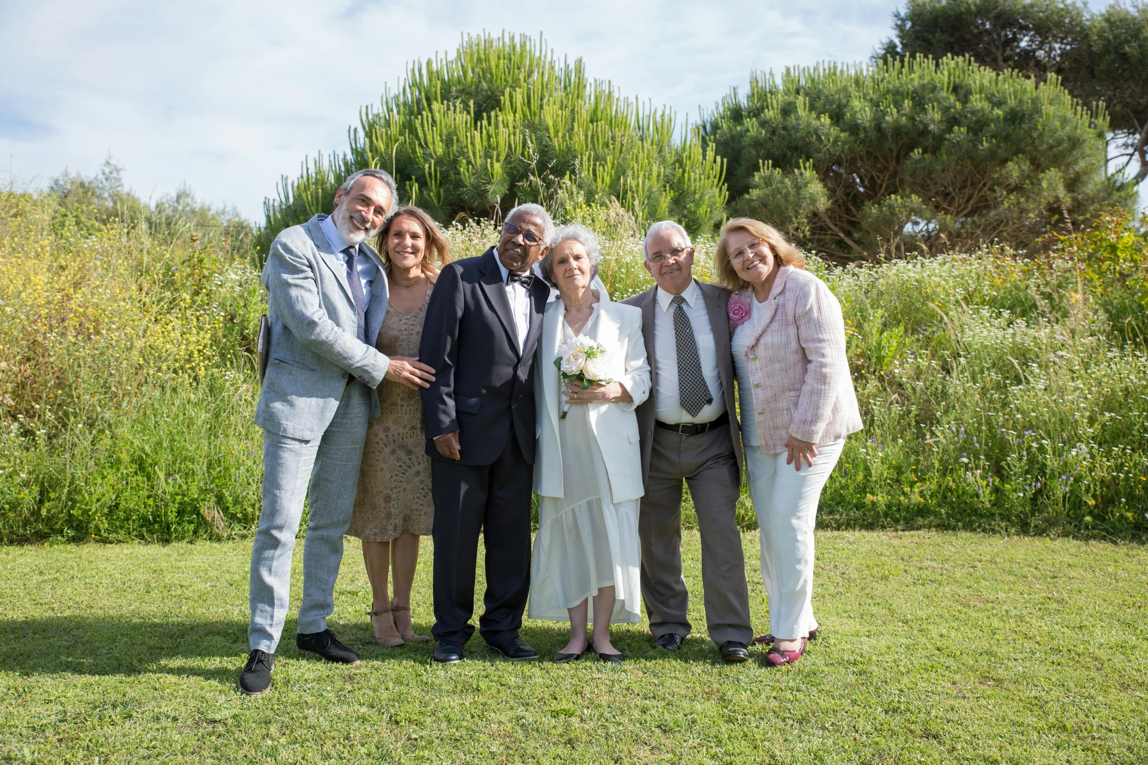 a group of people standing on top of a lush green field, traditional corsican, wedding photo, 70 years old, in a beachfront environment