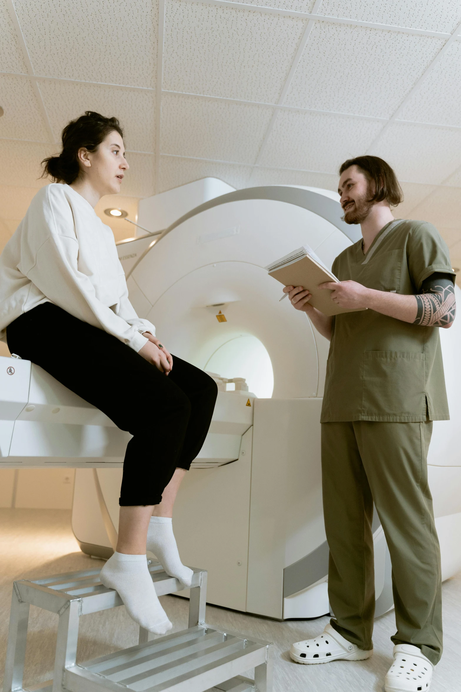 a man and a woman standing next to a mri machine, by Everett Warner, trending on pexels, renaissance, sitting on a table, woman is curved, thicc, high resolution scan