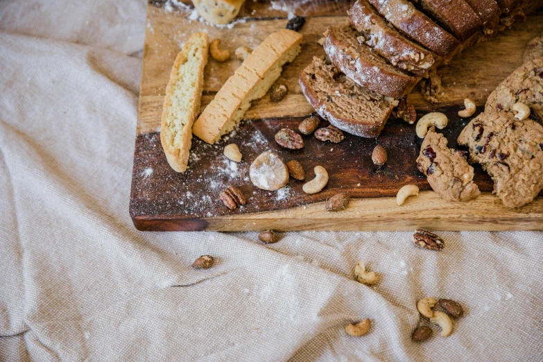 a wooden cutting board topped with bread and nuts, by Julia Pishtar, trending on pexels, cake, linen, background image, full body image