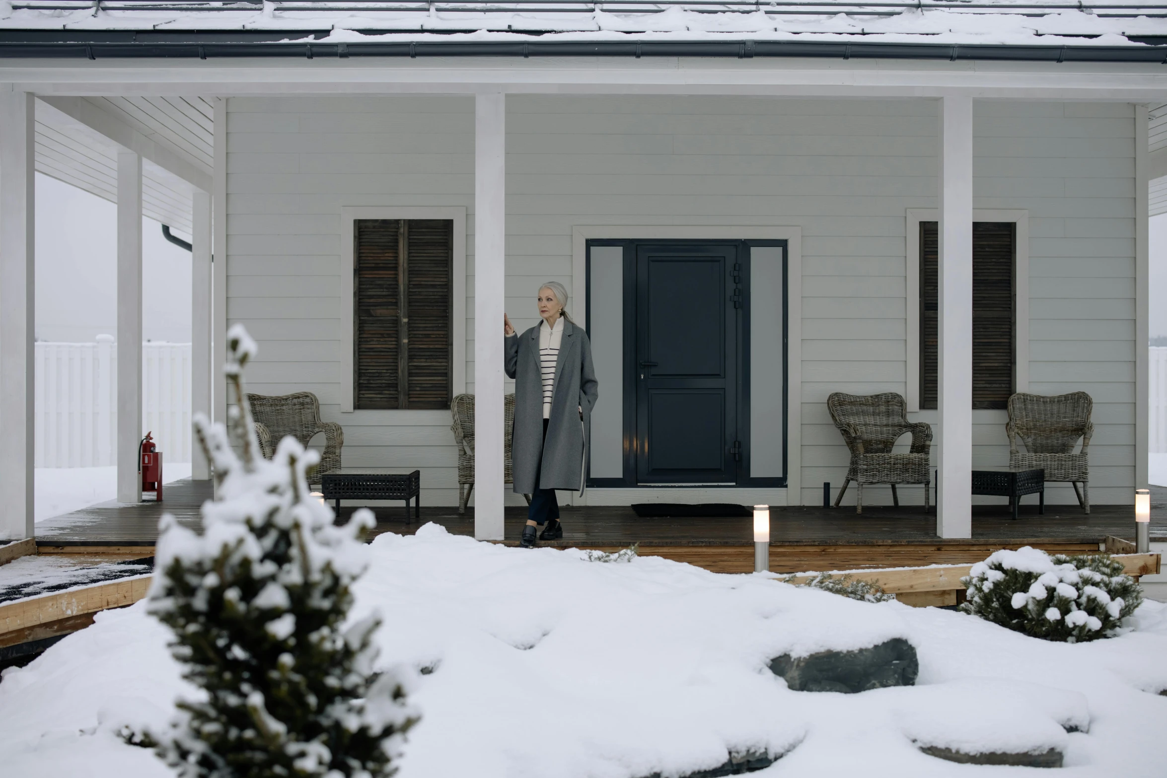 a woman standing outside of a house in the snow, a digital rendering, inspired by Eero Snellman, pexels contest winner, about to enter doorframe, still from the movie ex machina, 7 0 years old, in style of heikala