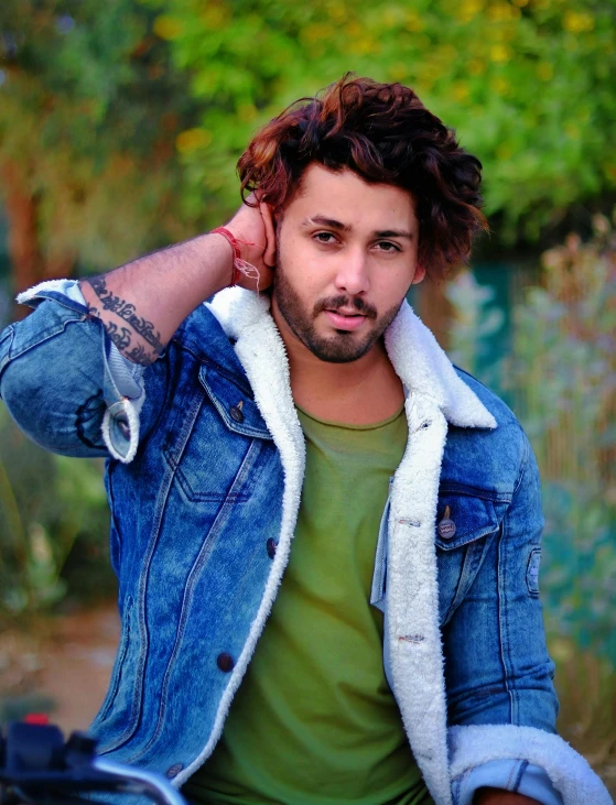 a man sitting on the back of a motorcycle, an album cover, by Shaddy Safadi, trending on pexels, handsome attractive face, wearing a blue jacket, tv still, hair