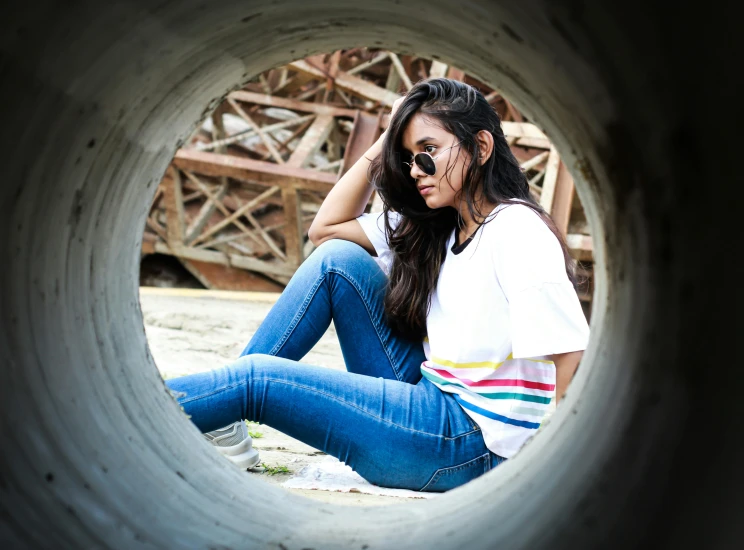 a woman sitting in the middle of a pipe, pexels contest winner, jeans and t shirt, multi colour, with sunglass, profile image