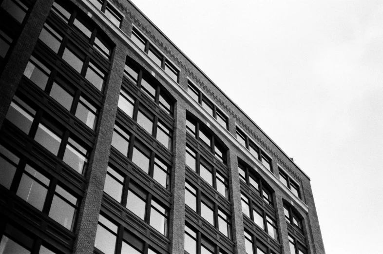 a black and white photo of a tall building, unsplash, brick building, konica minolta, high details photo, black windows