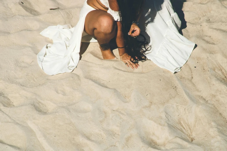 a woman kneeling on top of a sandy beach, pexels contest winner, wearing white silk, texture, tanned, wedding