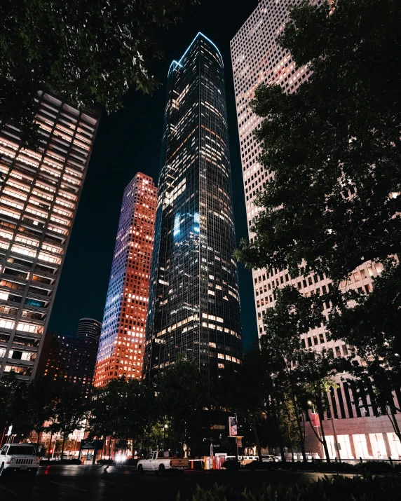 a group of tall buildings in a city at night, an album cover, unsplash contest winner, trending on vsco, city buildings on top of trees, 2 0 2 2 photo, world trade center twin towers