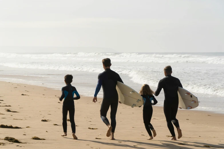 a group of people walking on a beach with surfboards, dad energy, portugal, profile image, fan favorite